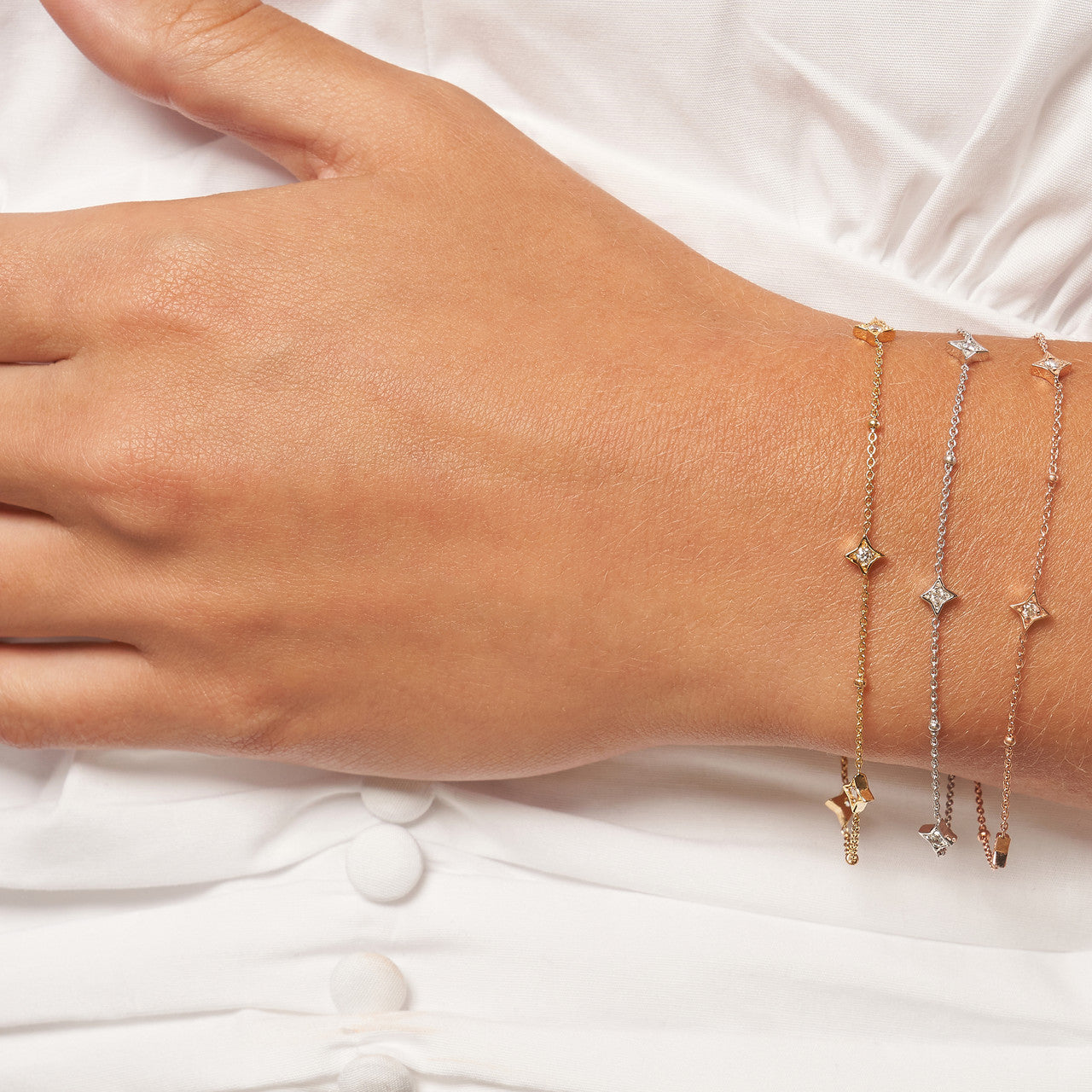 womans hand modeling the diamond star bezels and beads bracelet in rose gold, yellow gold, and white gold
