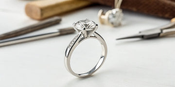 Diamond ring with a worn prong setting on a jeweler's workbench before repair.
