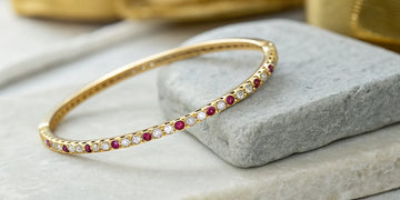 Roberto Coin bangle with diamonds and the signature ruby in 18k yellow gold.