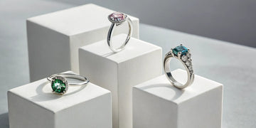 Three different two-stone birthstone rings with green, pink, and blue gemstones.