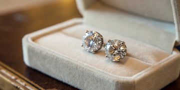 A pair of round brilliant cut diamond stud earrings in a jewelry box.