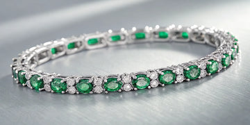 Emerald and diamond tennis bracelet with alternating oval emeralds and round diamonds.