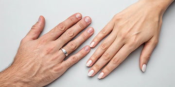 Male and female hands with engagement rings on the traditional ring finger.