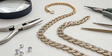 A broken necklace chain and the jewelry tools needed to fix it.