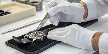 Expert watchmaker performing high-end watch servicing on a luxury movement.
