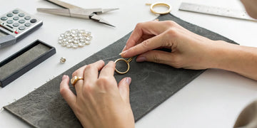 Jeweler using tools to resize a gold ring, a process that determines the final resizing cost.