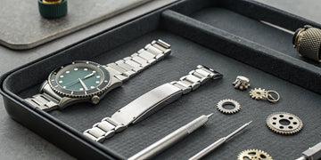 A disassembled Rolex watch on a tray for service, showing the parts that determine how much it costs.