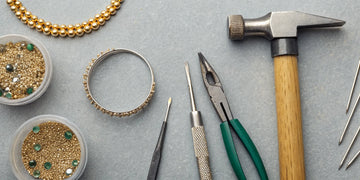 A collection of jewelry tools, gemstones, and a gold band ready to create your own ring.