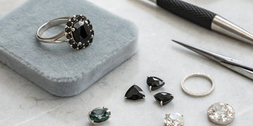 Designing your own black diamond engagement ring with loose stones and tools.