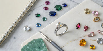 Designing your own engagement ring with loose gemstones and jeweler's tools.