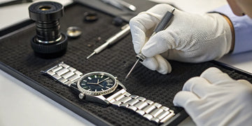 A watchmaker performs a Citizen Eco-Drive watch repair with precision tools.