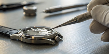 Local watchmaker fixing a broken watch crown with a tool.