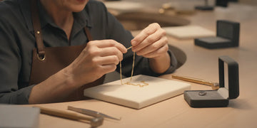Gold jewelry being examined closely under a jeweler’s loupe on a clean work surface