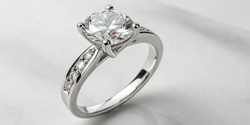 A round diamond engagement ring before a planned diamond upgrade.