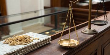 Gold jewelry being valued on a scale at a pawn shop or gold buyer.