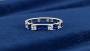 Elegant sapphire anniversary band in white gold setting resting on velvet, showing deep blue gemstones with gentle sparkle
