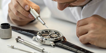 A watchmaker performs a luxury watch repair with precision tools.