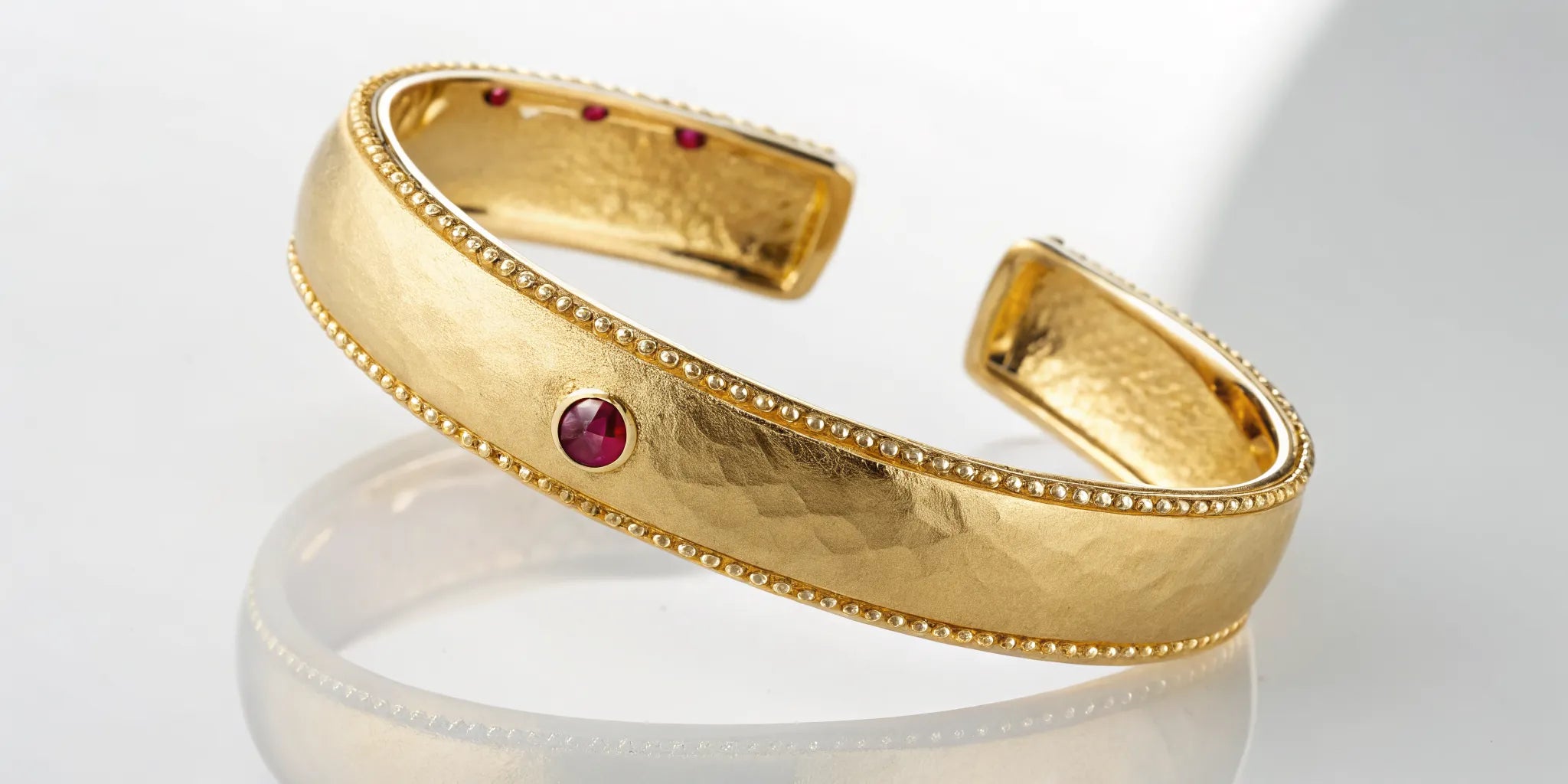 Roberto Coin gold cuff bracelet with its signature ruby and beaded edges.
