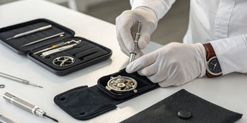 A technician's hands providing a mobile watch repair service on an open wristwatch.