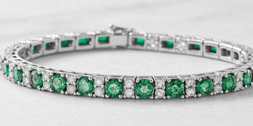 Diamond and emerald tennis bracelet with alternating round stones set in white gold.