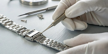 A watchmaker using precision tools to perform a watch clasp repair.