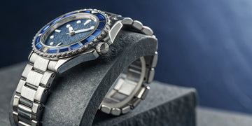 Rolex watch with a blue sapphire bezel and diamond accents.