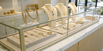 A display of designer gold jewelry including rings and necklaces at a jeweler in Oceanside, NY.