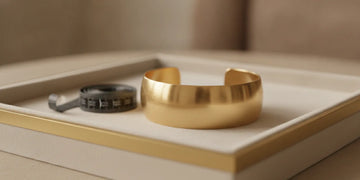 Gold bangle bracelet resting on a jewelry tray beside a measuring tape