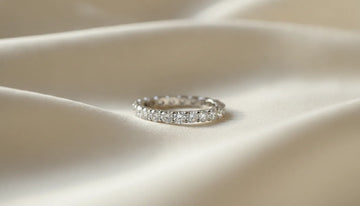 A diamond eternity band resting on soft cream silk in natural light