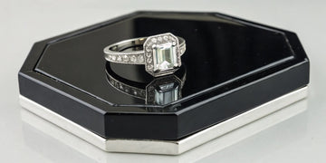Art deco platinum wedding ring with an emerald-cut diamond and pavé accents.