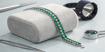 A real emerald bracelet with diamond accents on a jewelry display.