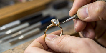 A jeweler crafting custom gold and diamond engagement and wedding rings.