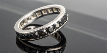 A mens black diamond eternity band in a modern channel setting.