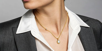 Roberto Coin gold initial necklace styled on a woman wearing a blazer.