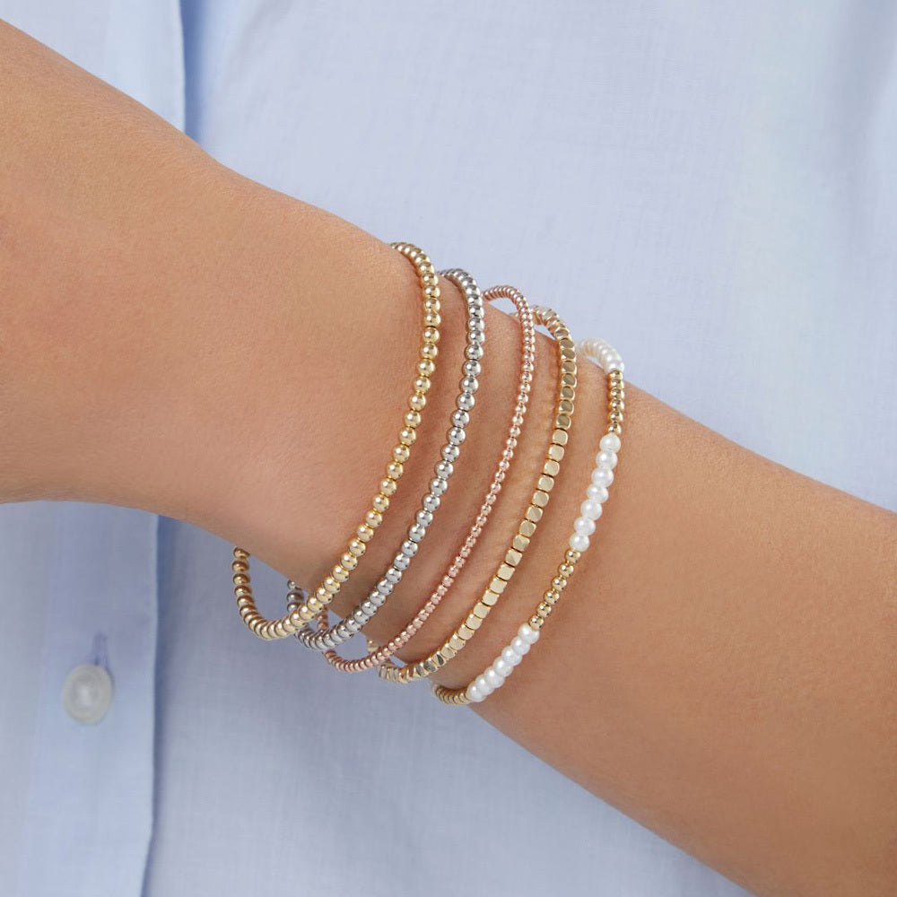 woman wearing multiple beaded bracelets including a rose gold bead bangle