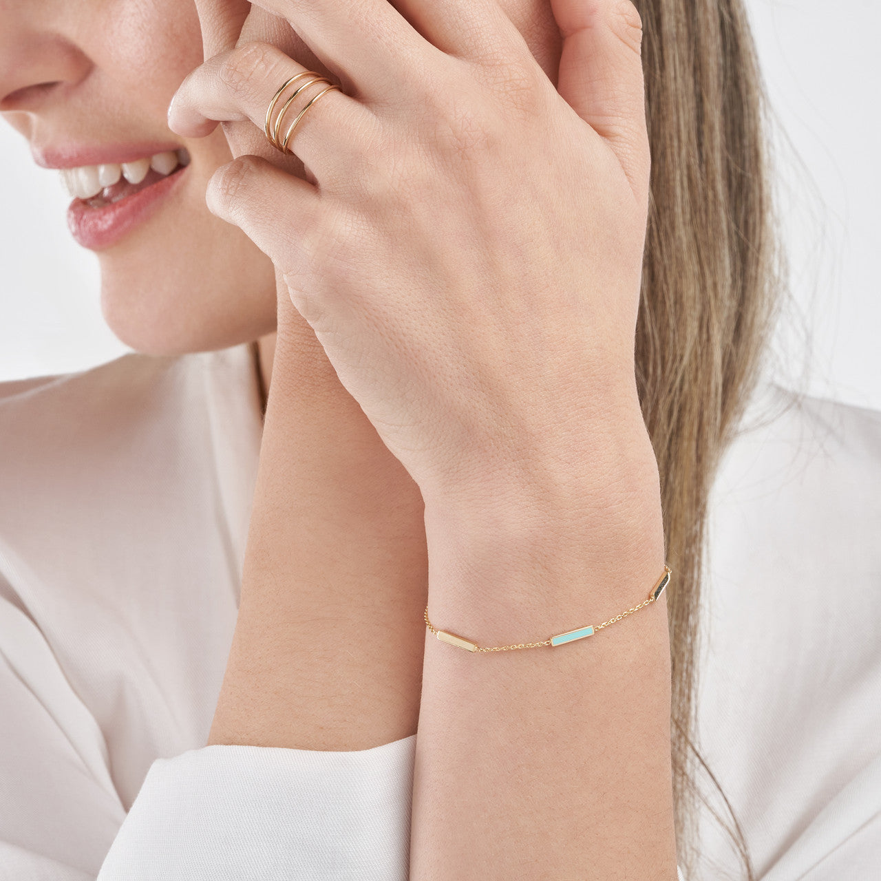 woman wearing the Turquoise Enamel Alternating Bar Station Bracelet on her wrist with her hand by her face