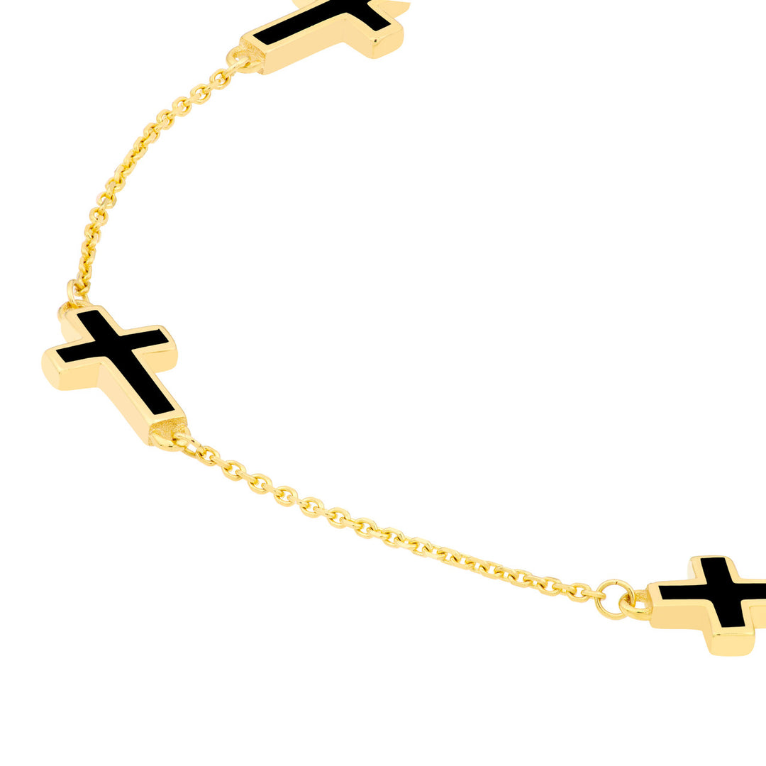 close up of the black enamel cross charm on yellow gold bracelet