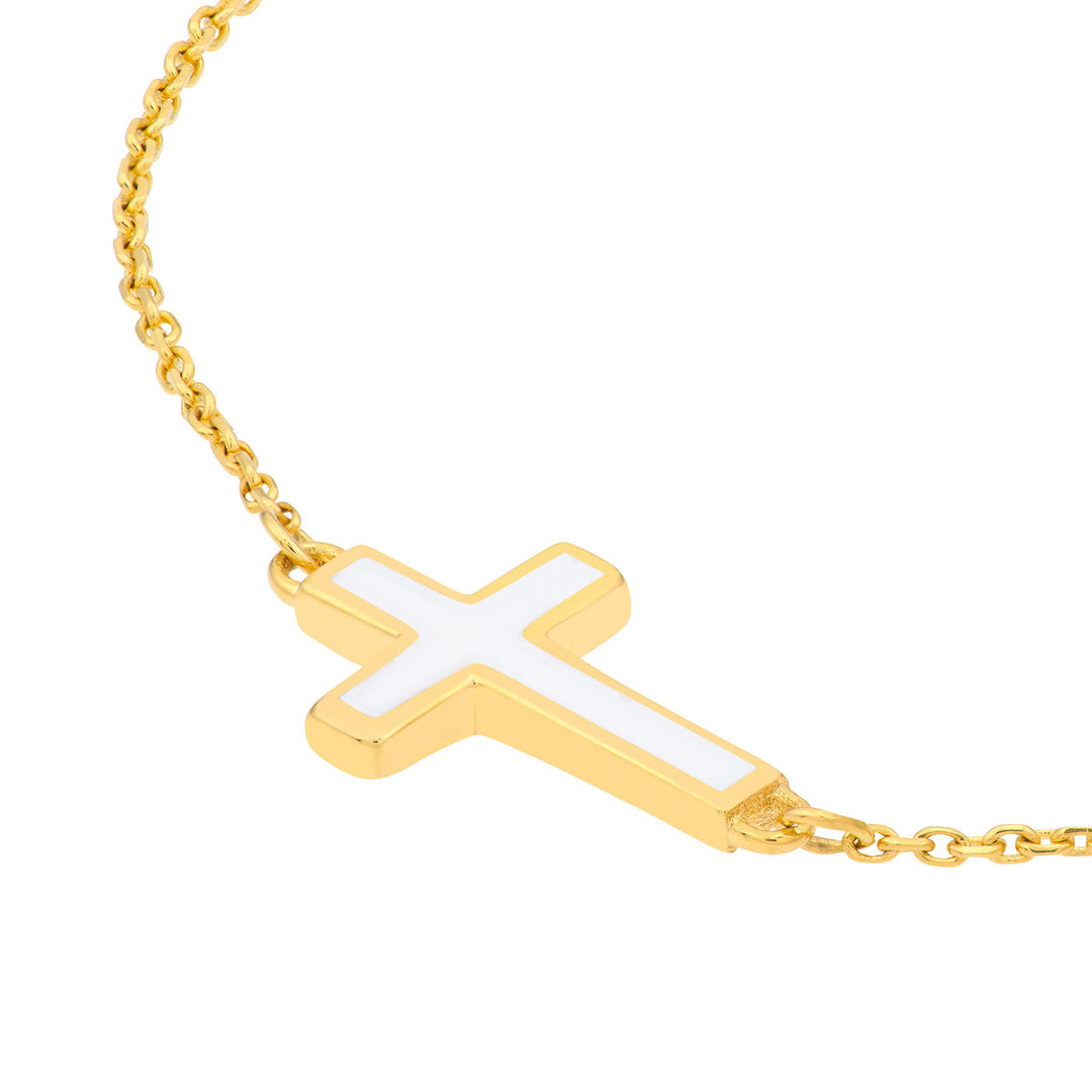 close up of the white enamel sideways cross on a yellow gold bracelet chain